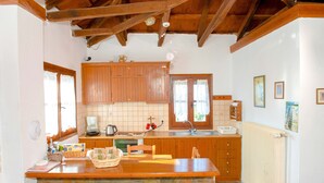 Eine Küche mit Holzschränken, einer Steinen Insel, einem Fenster mit Spitzenvorhängen und einer Heizung.