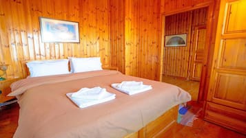 Ein Zimmer mit Holzwänden, einem Bett, zwei Kissen und zwei gefalteten Handtüchern auf dem Bett.