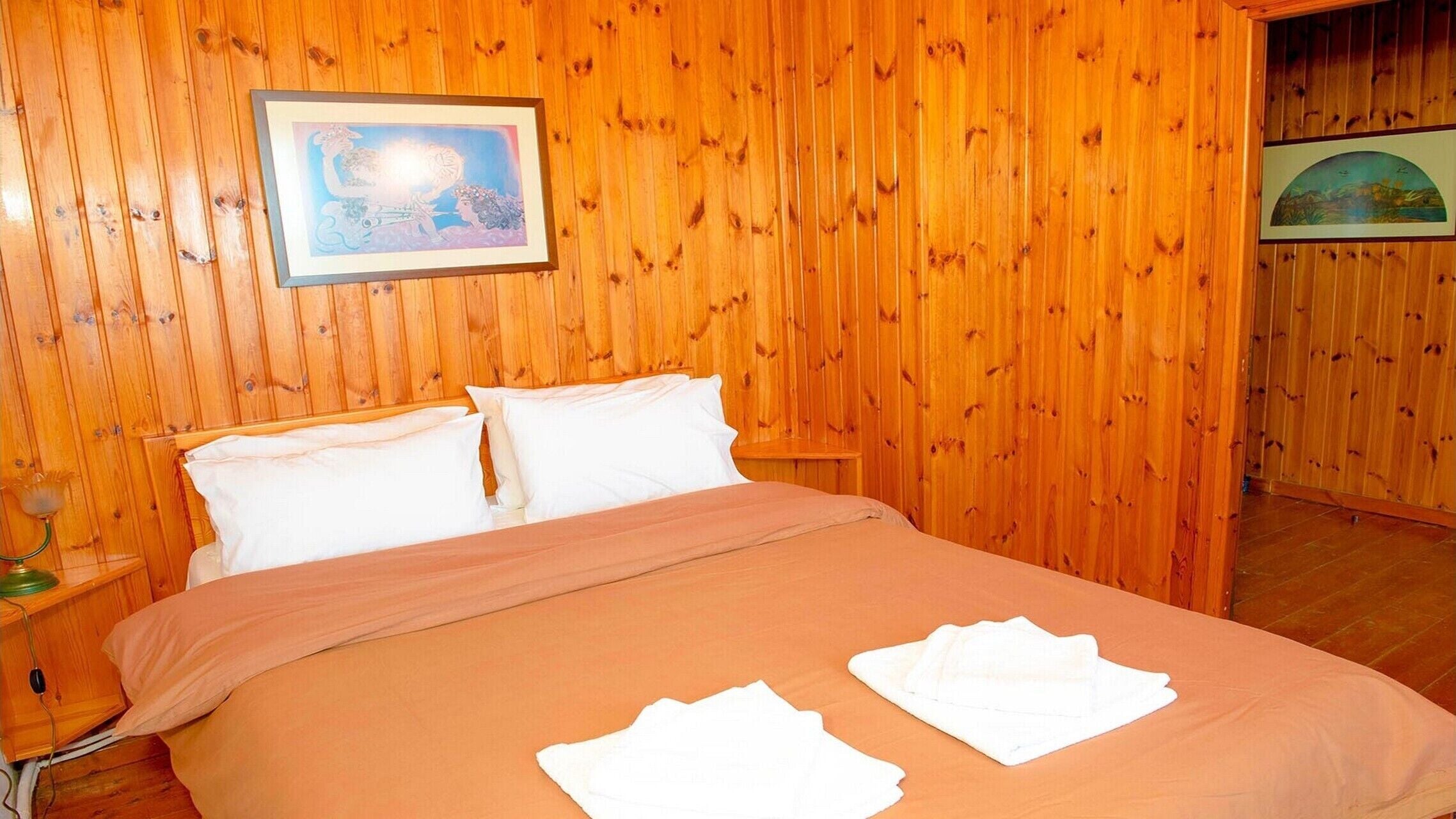 Ein Zimmer mit Holzwänden, einem Bett, Kissen und einem gerahmten Bild an der Wand.