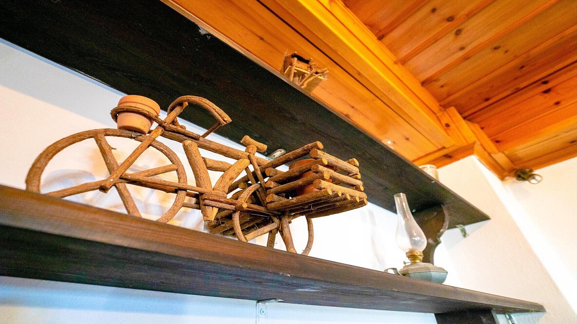A wooden shelf with a rustic bicycle decoration and a small vase.