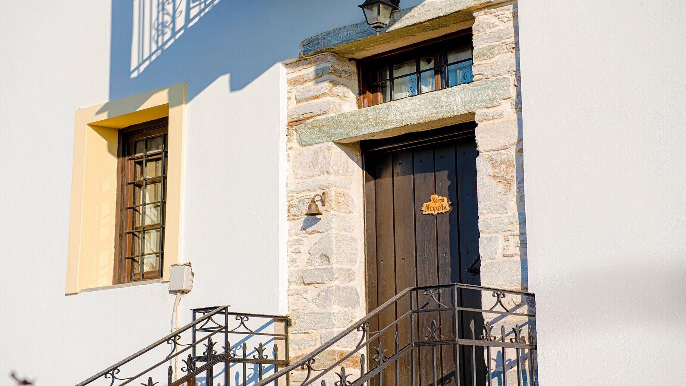 A building with a stone facade, a wooden door with a sign, and a window with a metal grille.