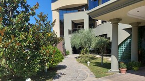 A courtyard with a paved pathway, surrounded by greenery and modern architecture. - Hotel Green (Vaqarr)