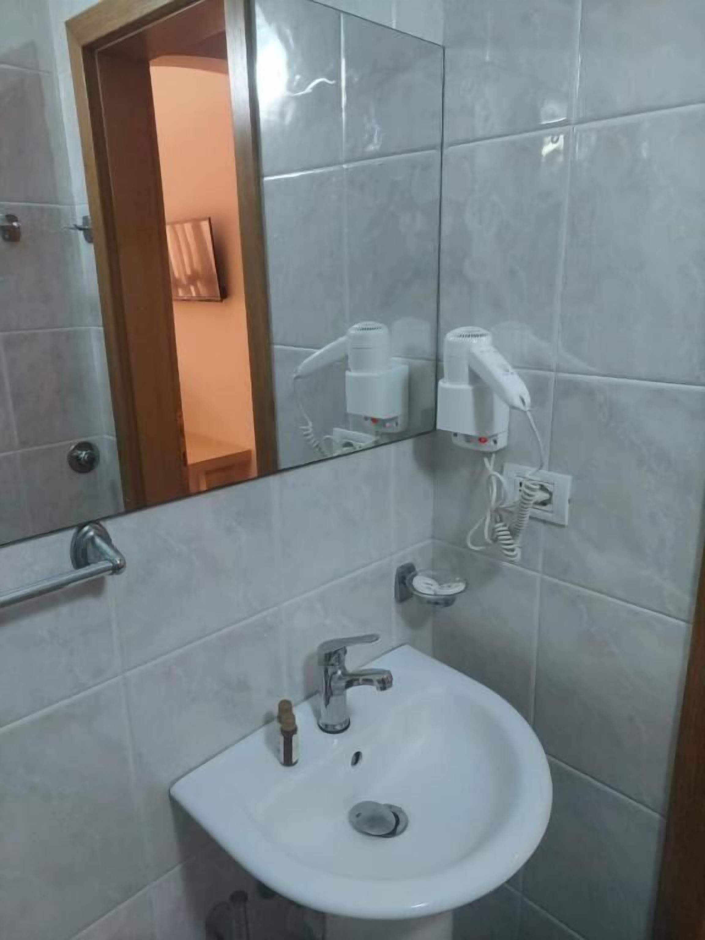 Un baño con un lavamanos blanco, un espejo y un dispensador de toallas.
