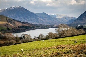 A scenic landscape with a lake, mountains, and grazing sheep. - Washington Central Hotel and Sleepwell Inn (Workington)