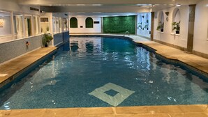 Una piscina interior con agua azul cristalina, paredes y suelo de baldosas.