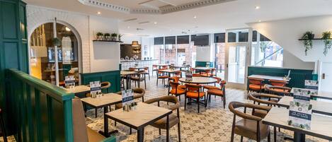 A spacious cafe with multiple seating areas, including tables and booths, and a visible counter area.