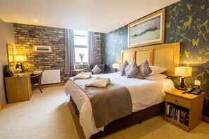 A hotel room with a large bed, bedside tables, a desk, and a radiator. - Washington Central Hotel and Sleepwell Inn (Workington)