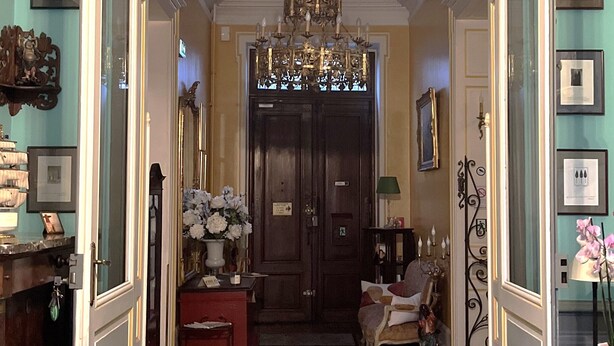 A hallway with a patterned floor, a chandelier, and a door leading to another room. - Chateau des Jacobins (Agen)