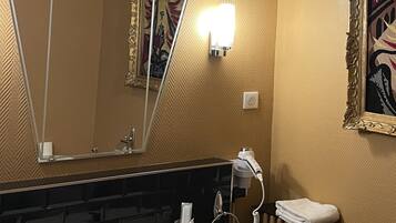 A bathroom with a white sink, a mirror, a towel rack, and a radiator.