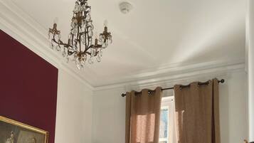 Habitación de hotel con cama, escritorio, silla, televisor y ventana con cortinas.