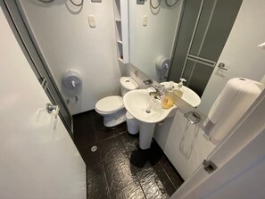 Une petite salle de bain avec des toilettes, un lavabo et un miroir.