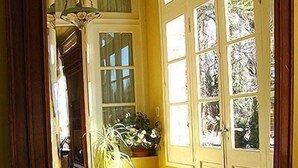 Un couloir avec un mur jaune, un escalier en bois et une porte dotée de plusieurs fenêtres.
