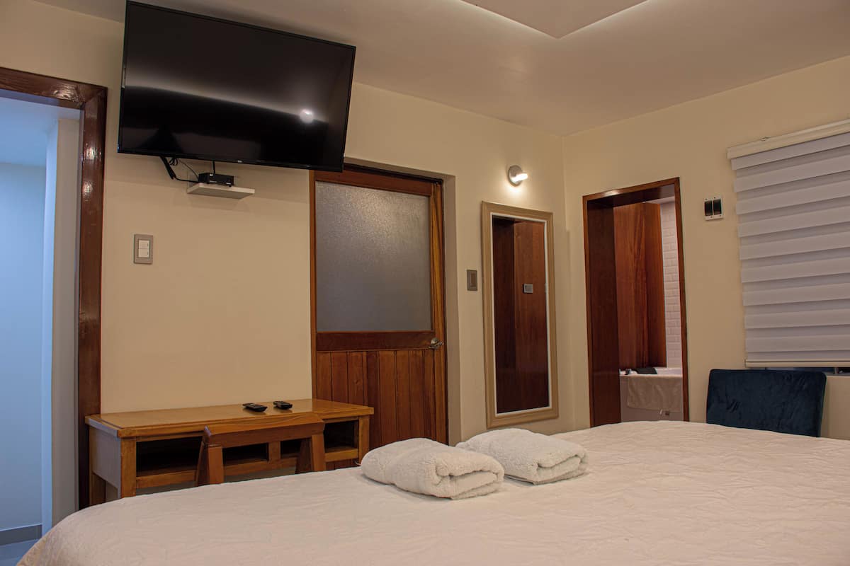 Ein Hotelzimmer mit Bett, Schreibtisch, Fernseher und einer Tür.