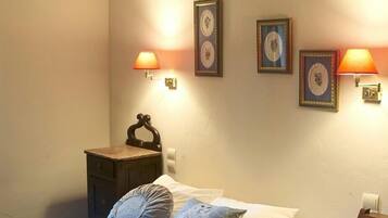 A bedroom with a bed, bedside lamps, a nightstand, and wall-mounted picture frames.