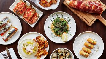 Una variedad de platos sobre una mesa de madera, entre ellos pescado, verduras y pan.