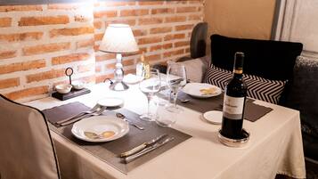 A dining table set with plates, cutlery, wine glasses, and a bottle of wine.