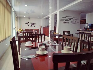 A dining area with wooden tables and chairs, a world map on the wall, and a coffee-themed word cloud.