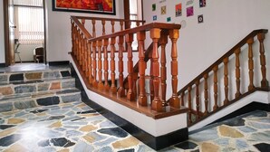 A staircase with wooden balusters, a tiled floor, and a wall decorated with postage stamps. - Hotel Confort Bogotá (Bogotá)