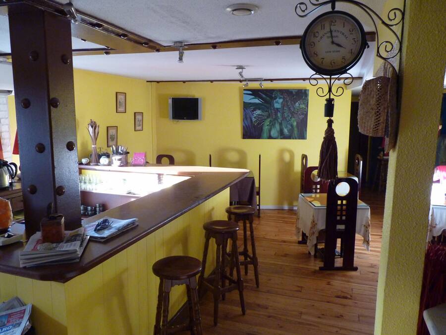 A bar area with a wooden counter, stools, and a hanging clock.