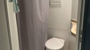 A bathroom with a white toilet, a beige sink, and a shower curtain.