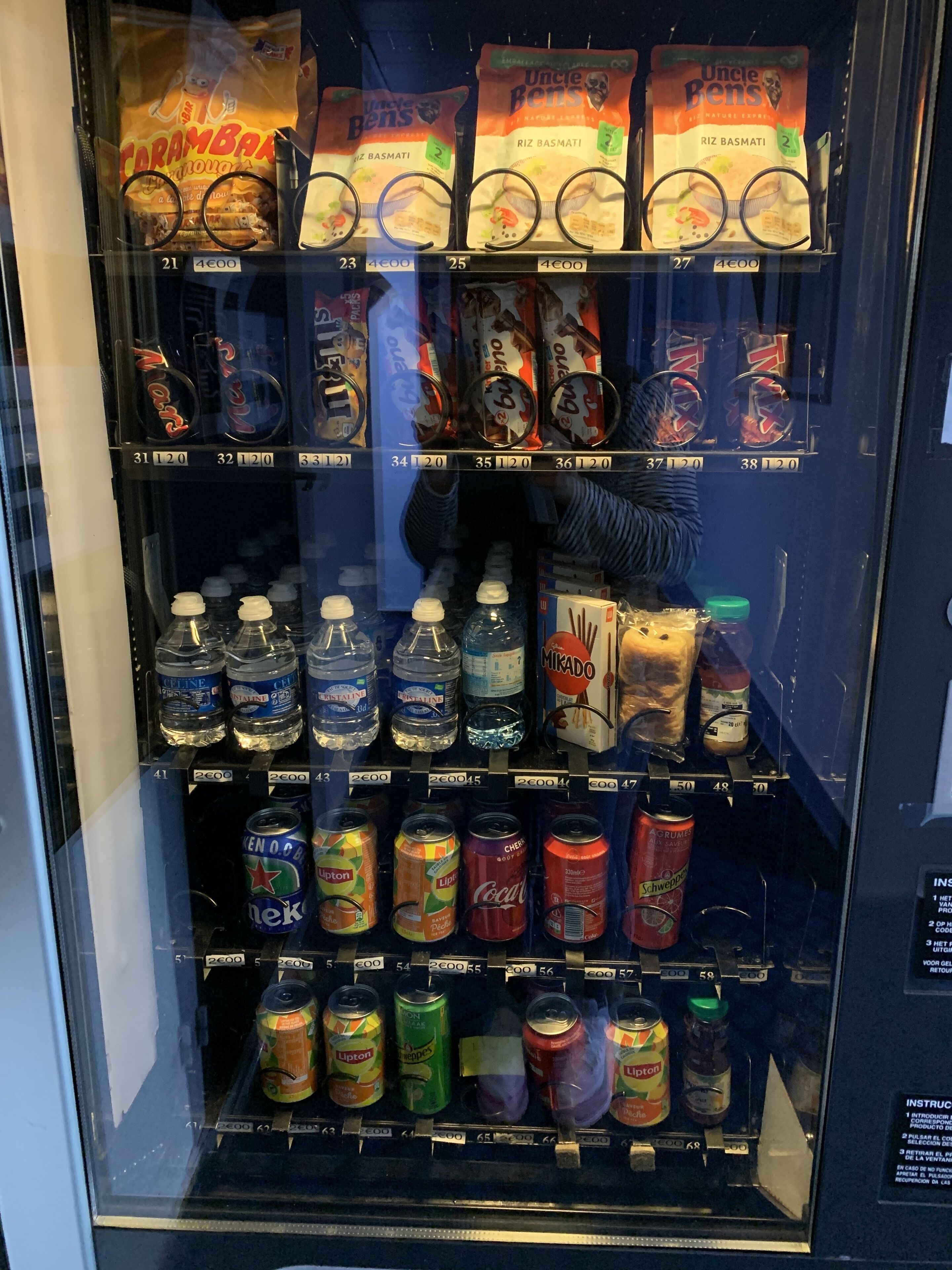 A vending machine stocked with snacks, bottled water, and canned beverages.
