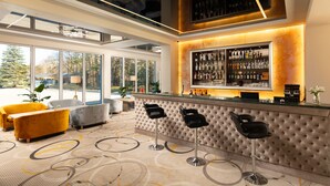 Un área de bar moderna con una barra, varios taburetes y un ventanal con vistas al exterior.