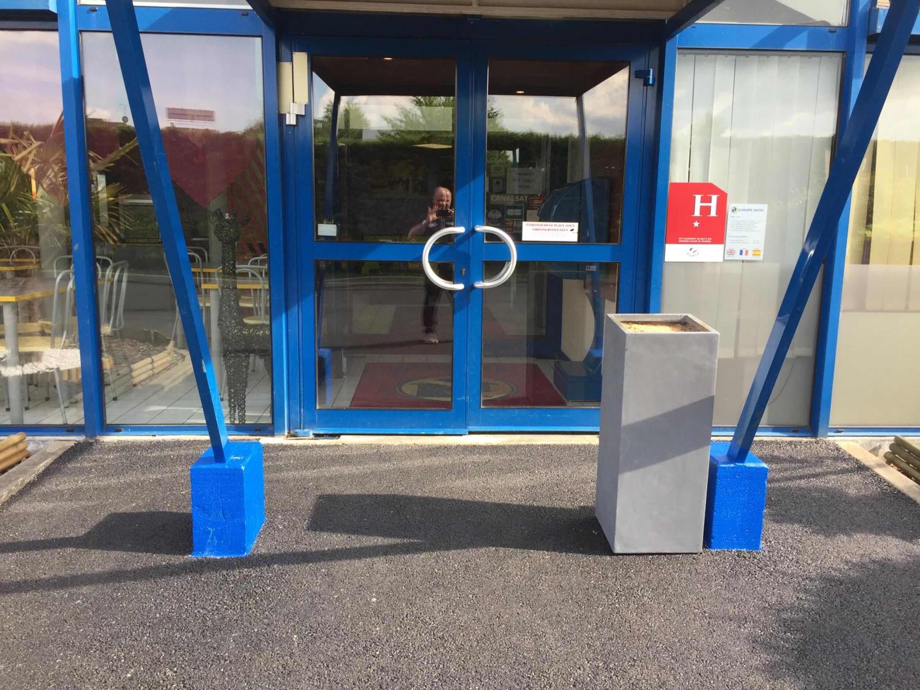 Un edificio azul con puerta de cristal y un cartel que indica un hotel.