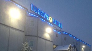 Een hotel met een bord waarop 'EUROPE HOTEL' staat en een auto met een laag sneeuw ervoor geparkeerd.