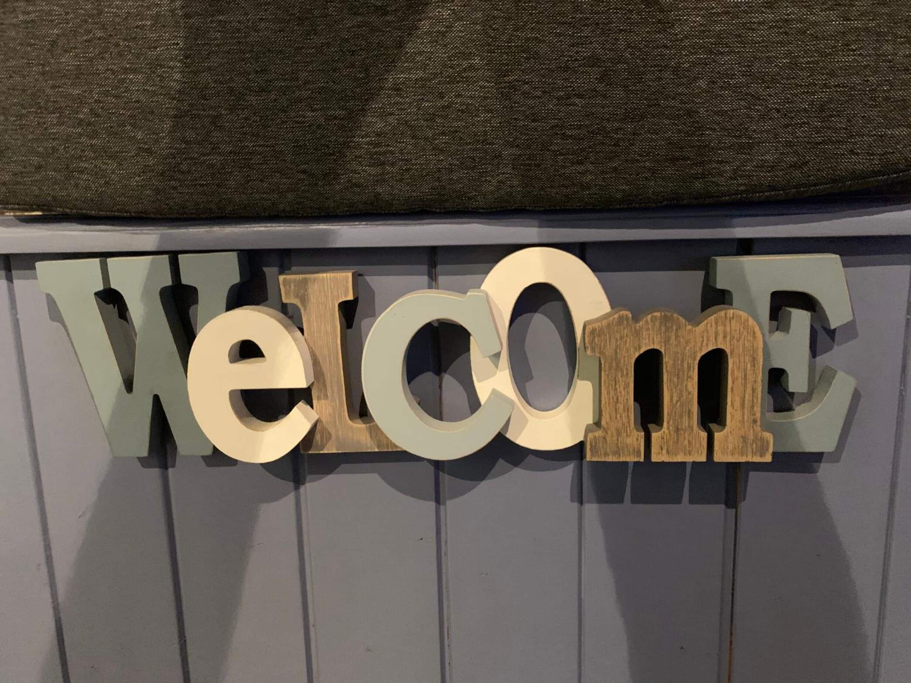 A wall-mounted sign with the word "Welcome" in a mix of materials and colors.