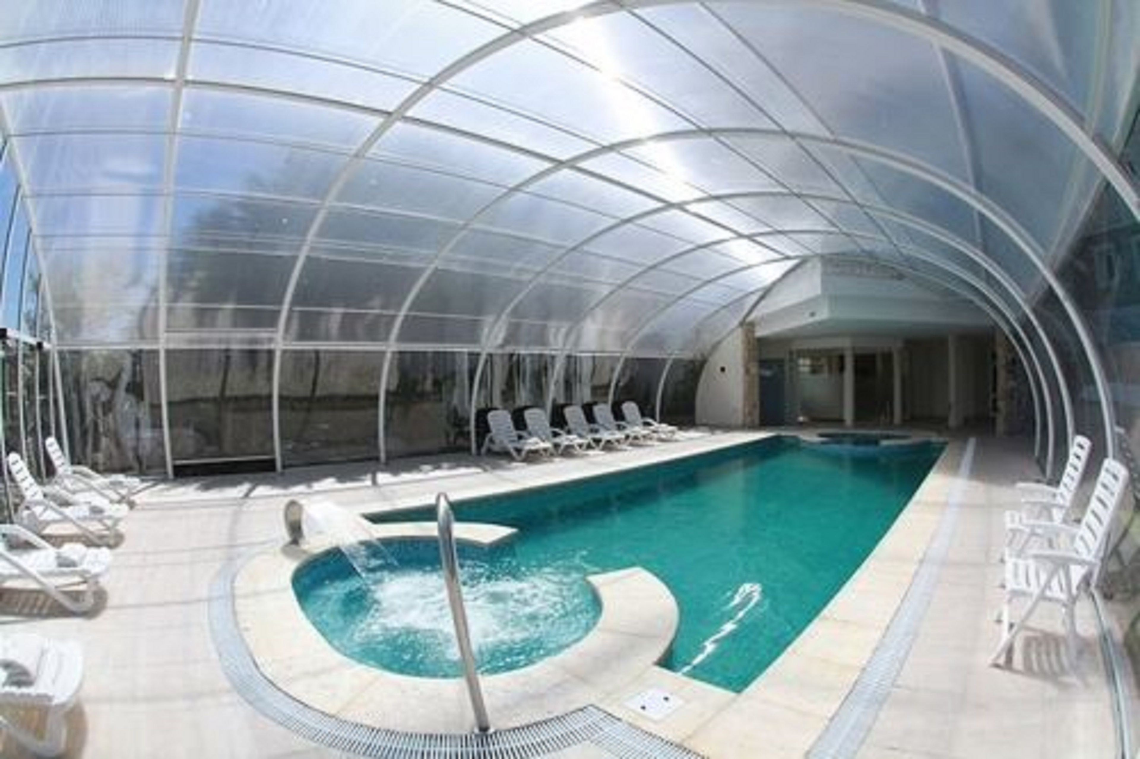 Una piscina techada con sillas de descanso y un jacuzzi.