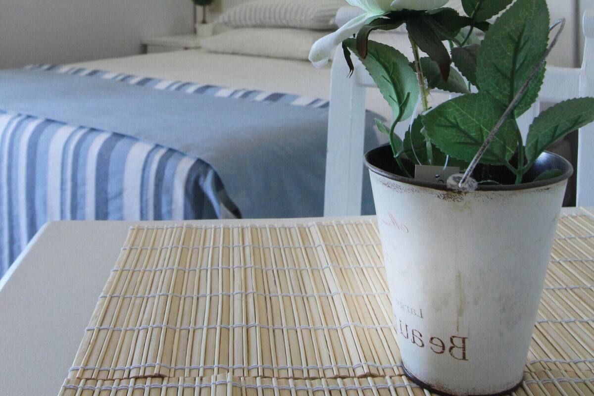 A hotel room with a bed, a bedside table with a potted plant, and two wall-mounted lamps.