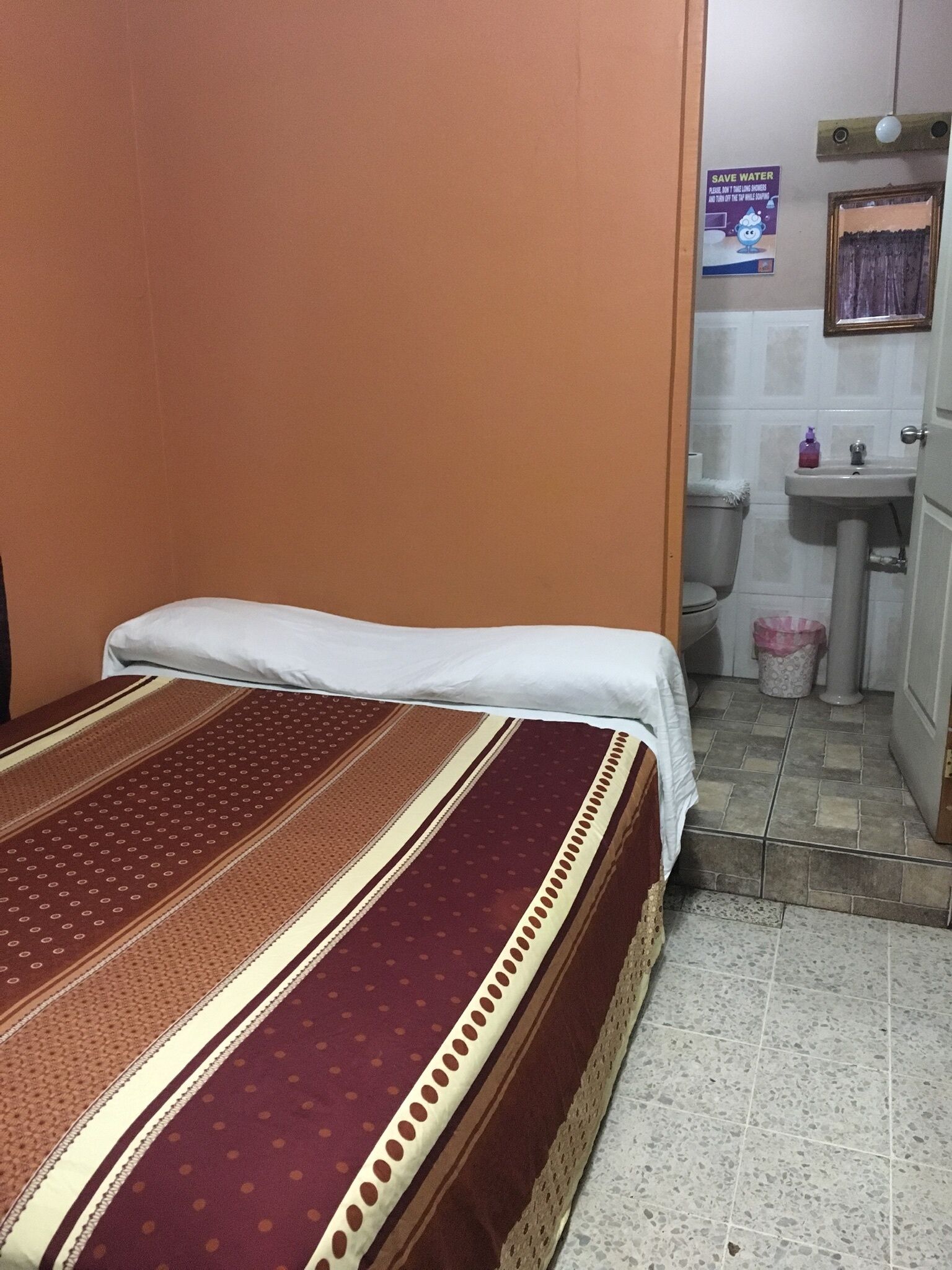 A small, simple room with a bed, a sink, and a toilet.