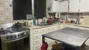 A kitchen with a stove, oven, and cabinets. There is a sign on the wall and various kitchen utensils and appliances. - Tamarindo hostel (San Pedro Sula)