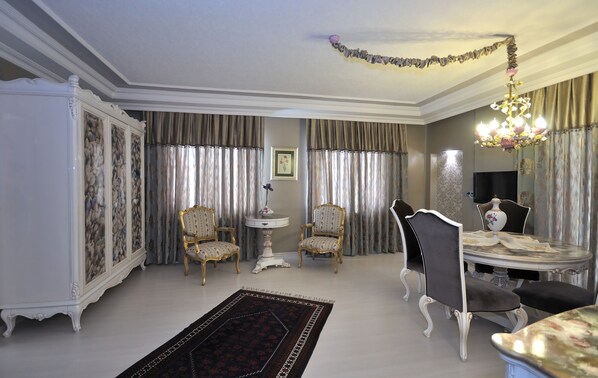 A room with a dining table, two chairs, a sideboard, and a chandelier.