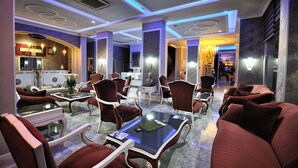 A hotel lobby with a reception desk, seating area with armchairs and tables, and a chandelier. - Grand Atakum Hotel (Atakum)
