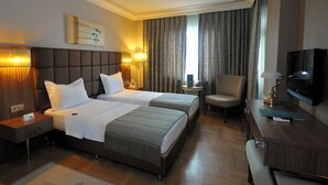 A hotel room with two beds, a television, a desk, and a chair. - Grand Atakum Hotel (Atakum)