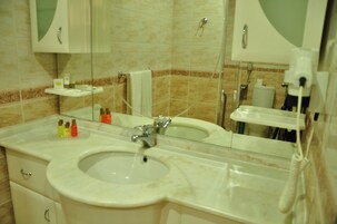Un baño con lavamanos doble, espejo, toallero y inodoro.
