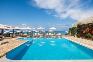 Una piscina al aire libre, sombrillas, sillones reclinables de piscina