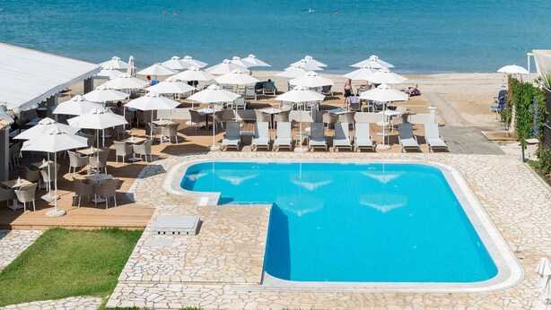 Un espace aménagé au bord de la piscine, avec des chaises longues et des parasols, une piscine et une vue sur l’océan.