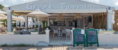 A Greek tavern with outdoor seating and a covered patio.