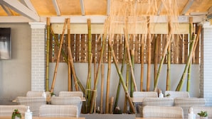 Un restaurant avec des meubles en osier, une décoration à base de bambou et un sol en pierre.