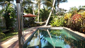 Una piscina al aire libre, sombrillas, sillones reclinables de piscina
