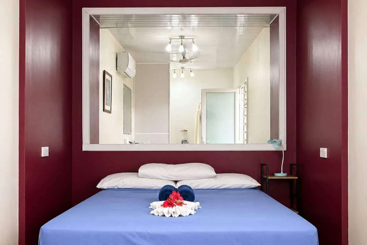 Een kamer met een groot bed, een spiegel en een houten vloer.