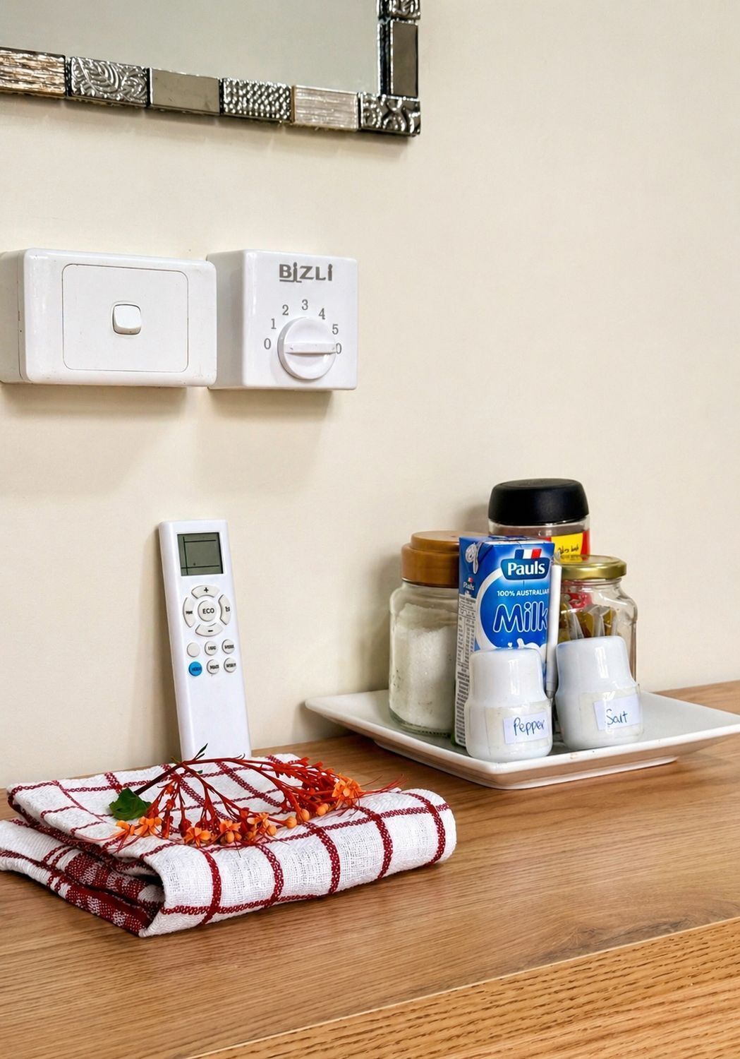 A kitchen with a microwave, a BIZLI timer, a digital control panel, and a plate with milk, pepper, and salt.