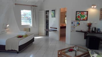 A bedroom with a bed, bedside table, and a window with curtains. There is a door leading to a bathroom.