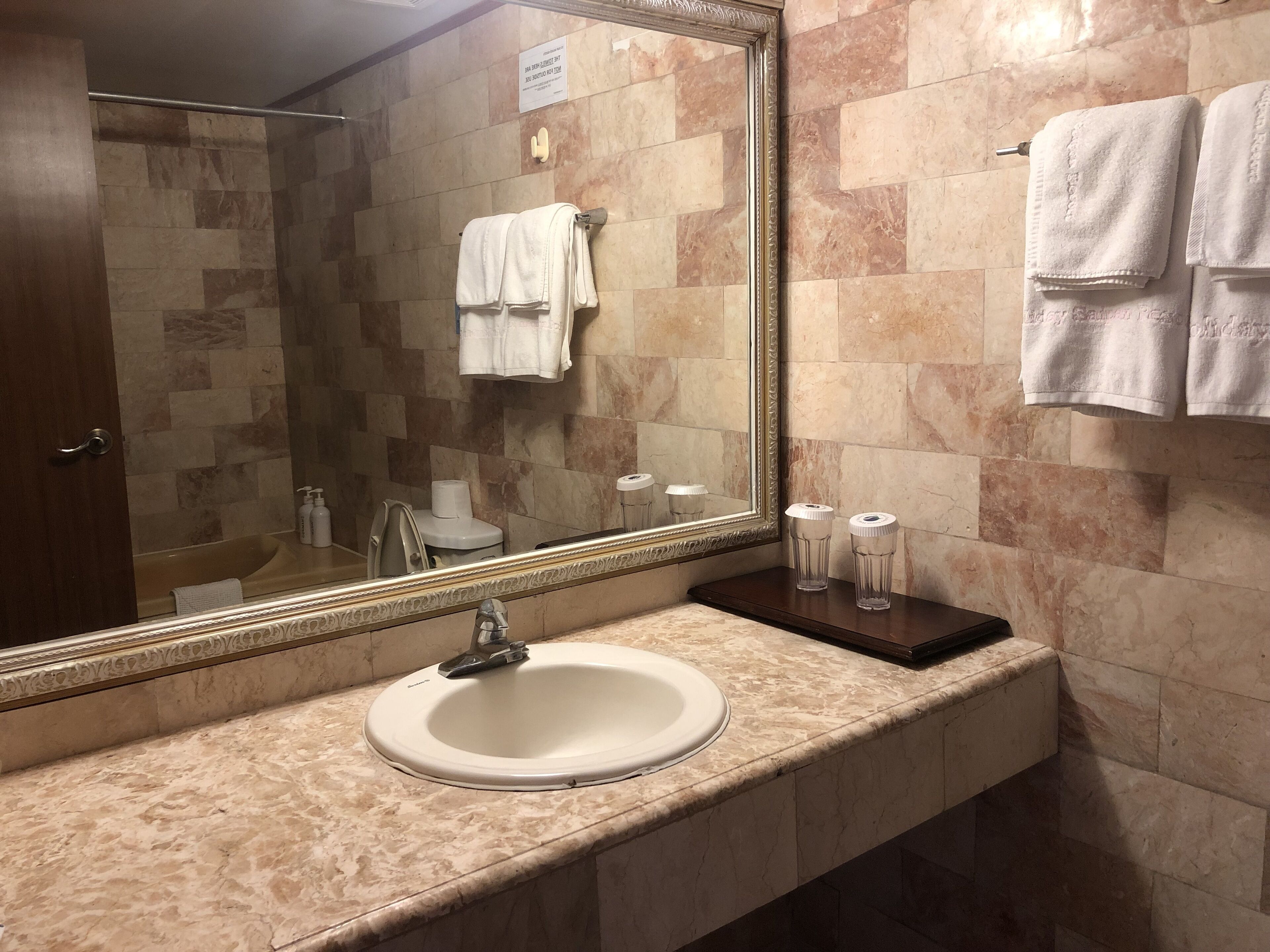 A bathroom with a marble sink, a large mirror, and a towel rack.