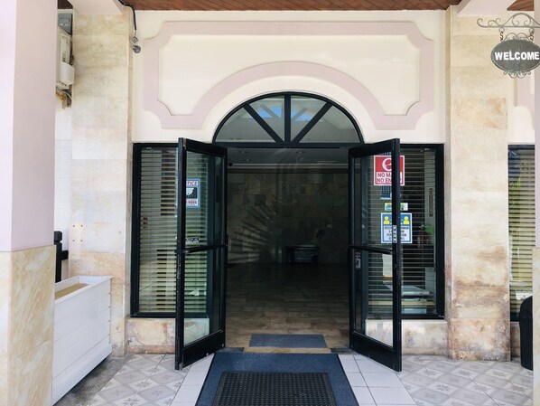 A hotel entrance with a glass door, a welcome sign, and a no entry sign. - Holiday Saipan Hotel (Saipan)