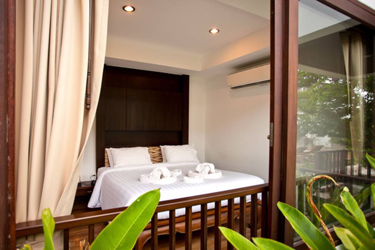 A bedroom with a bed, pillows, a bedside table, and a window with curtains.