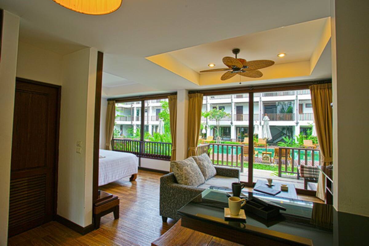 A hotel room with a bed, a sofa, a coffee table, and a view of the outdoor balcony.