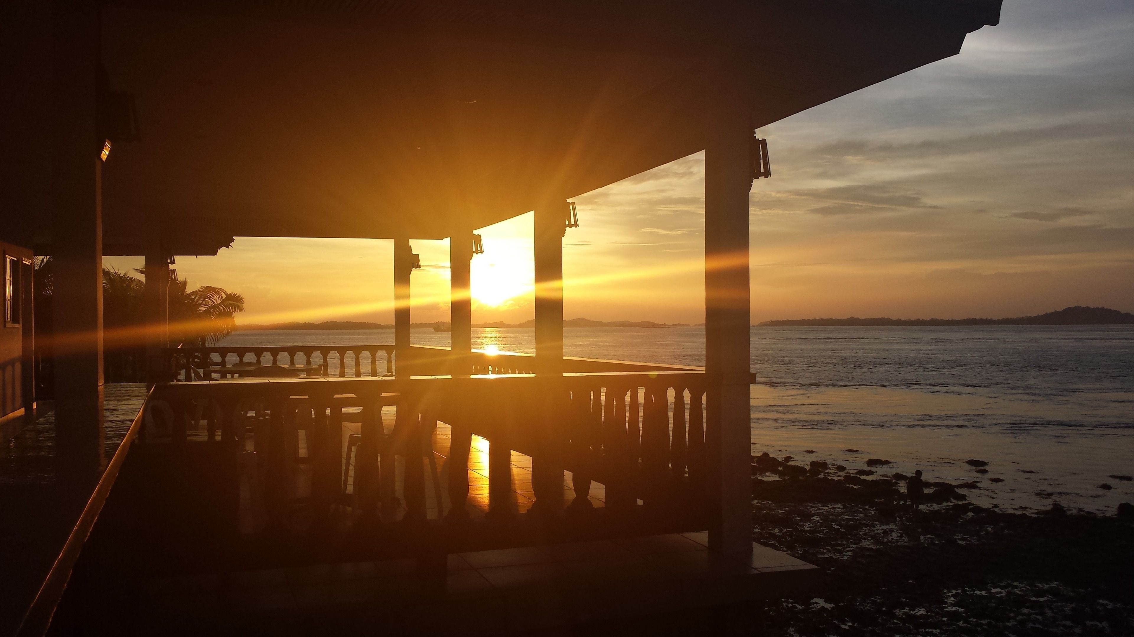 Une vue sur la côte, avec un coucher de soleil, une jetée et une plage.
